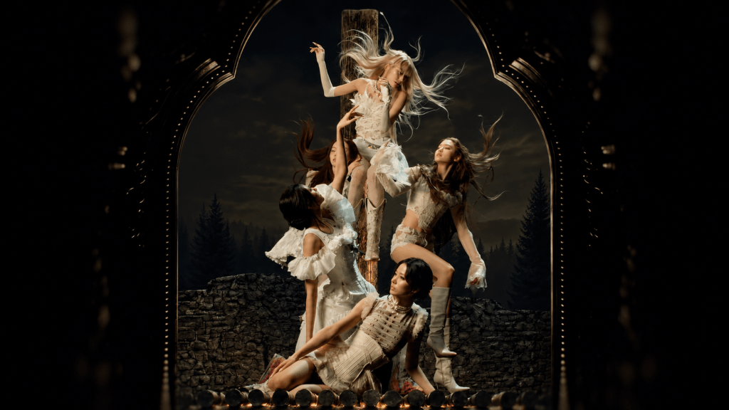 A gothic, painting-like tableau from the “DDI RO RI” music video, with the performers posed around a stake or cross-like wooden structure inside an ornate frame.